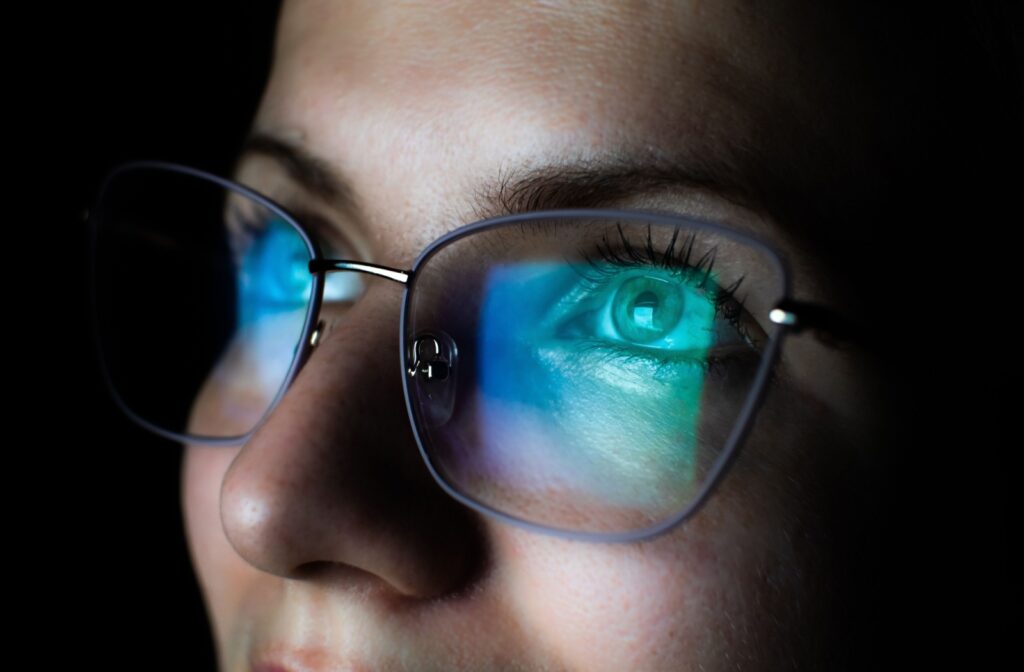 A woman's face close-up, looking up with blue light glasses.