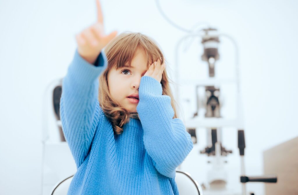 A young girl covers her eye during her comprehensive eye exam.