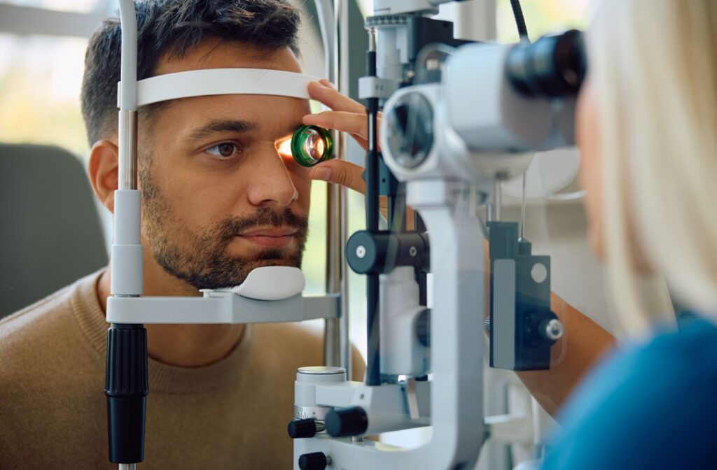Patient undergoing eye exam while optometrist shines a light into one eye.