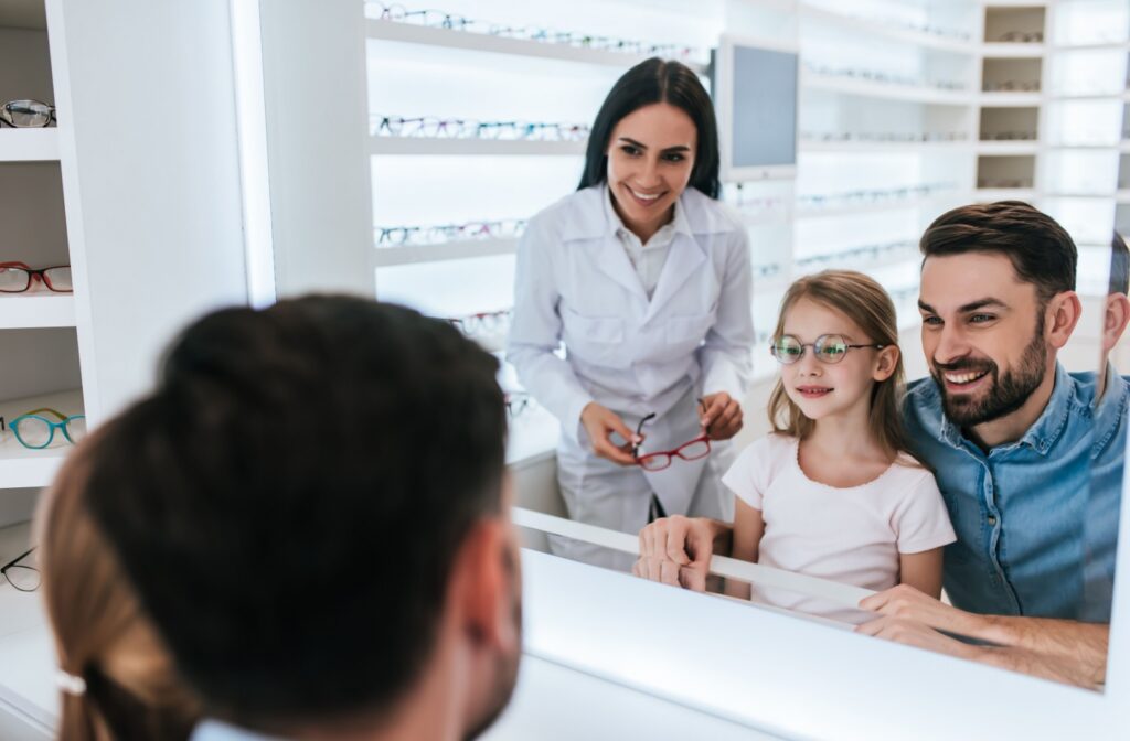 Smiling young patient with father and optometrist with new glasses