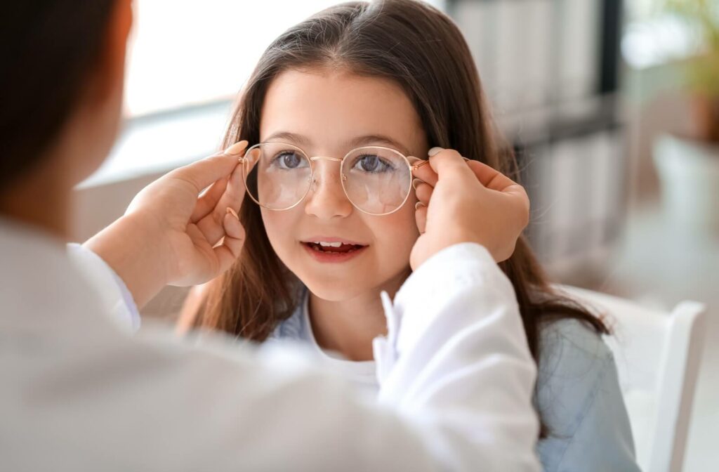 An eye care professional adjusting a pair of eyeglasses on a child during an appointment.