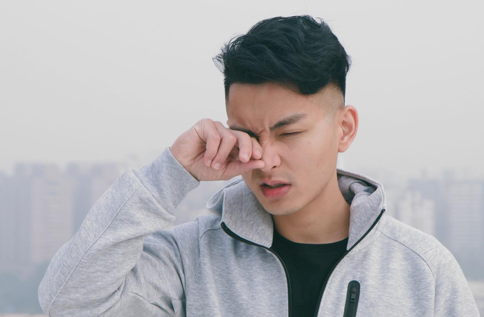 A person rubbing their eyes while out on a run